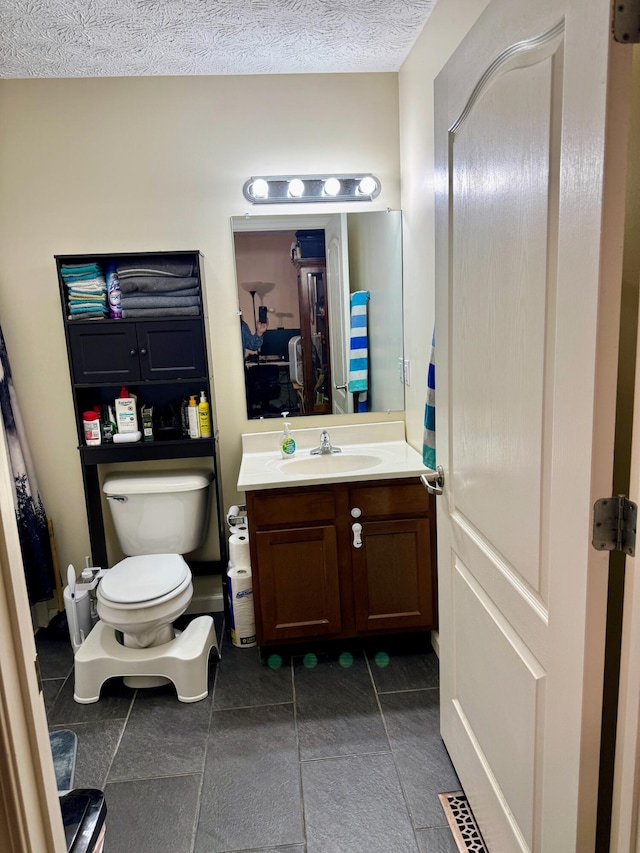 bathroom with a textured ceiling, tile patterned flooring, vanity, and toilet