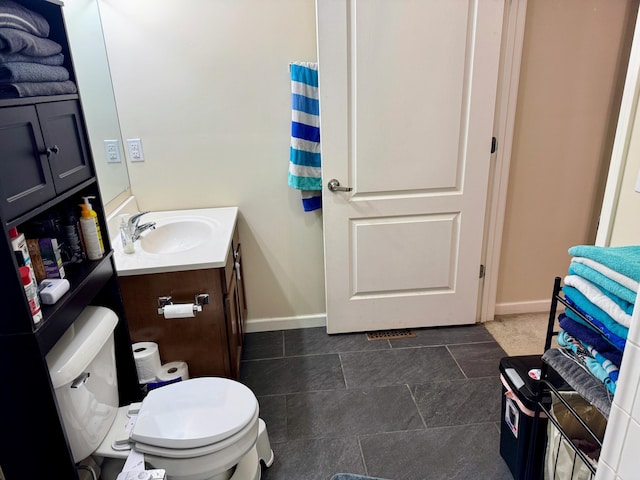 bathroom featuring toilet, vanity, and baseboards