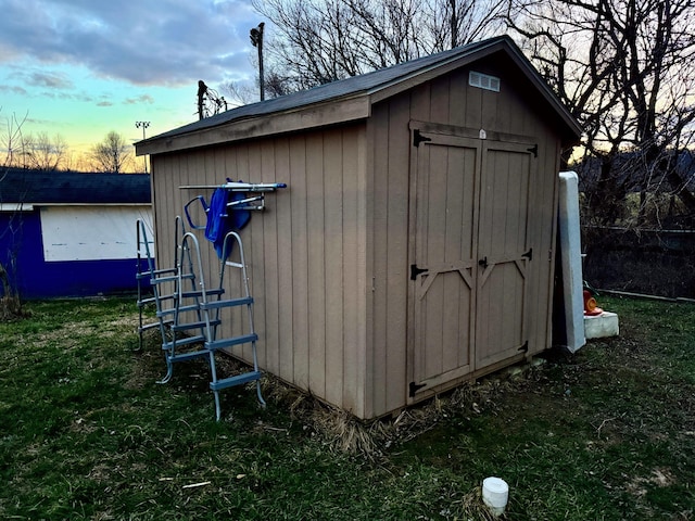 outdoor structure at dusk with an outdoor structure, a lawn, and a shed