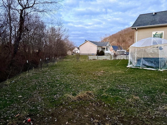 view of yard featuring a greenhouse, fence, and an outdoor structure