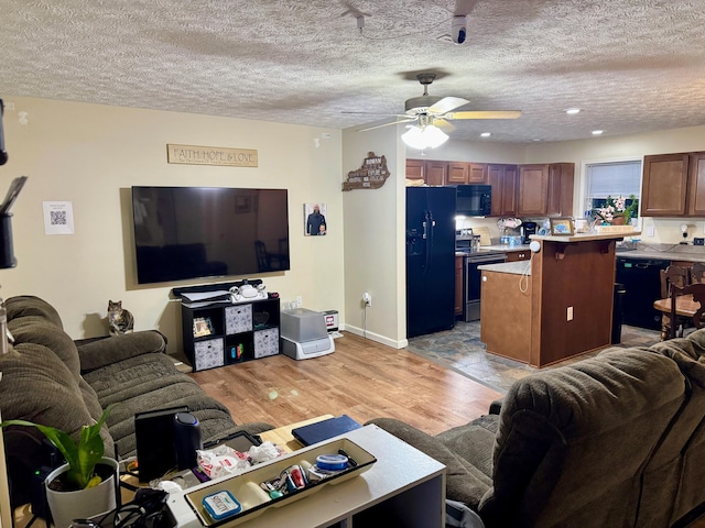 living area with light wood-style flooring, ceiling fan, and a textured ceiling