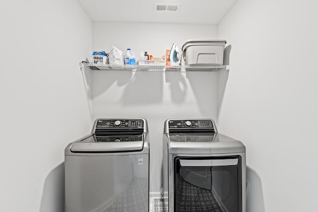 washroom with laundry area, washing machine and clothes dryer, and visible vents