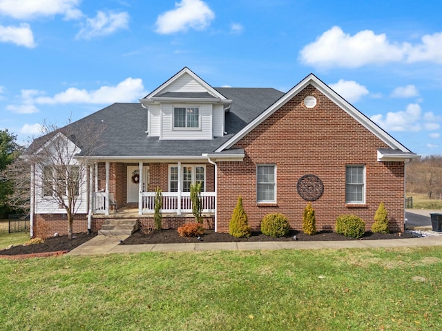 view of front facade featuring a shingled roof, covered porch, brick siding, and a front lawn