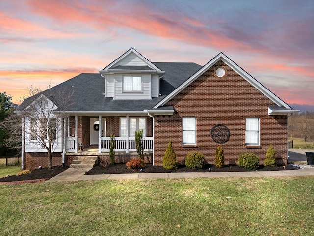 traditional-style home with brick siding, covered porch, and a yard