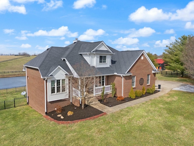 traditional home with fence, driveway, a porch, a front lawn, and brick siding