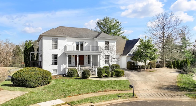 view of front of property with a porch, a balcony, concrete driveway, french doors, and a front yard