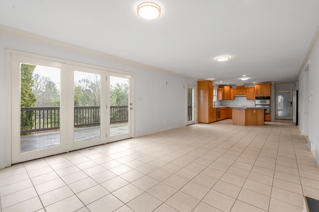 unfurnished living room with baseboards, crown molding, and light tile patterned flooring