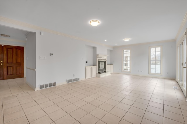 unfurnished living room featuring visible vents, a glass covered fireplace, crown molding, and light tile patterned flooring