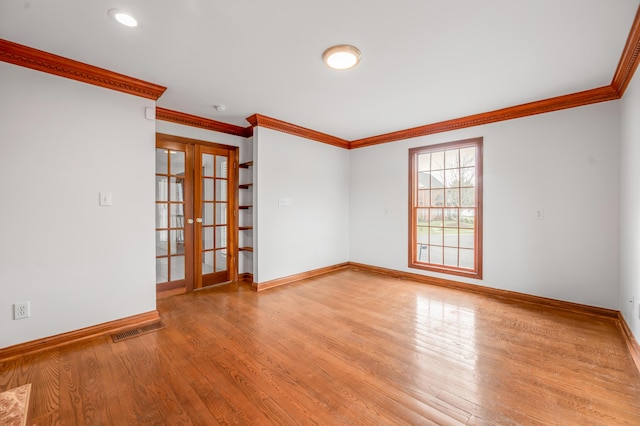 unfurnished room with wood finished floors, visible vents, baseboards, ornamental molding, and french doors