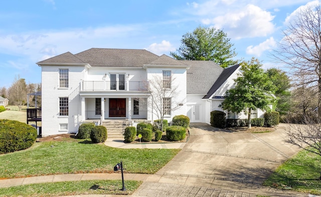 view of front of property with a porch, a balcony, driveway, stucco siding, and a front lawn