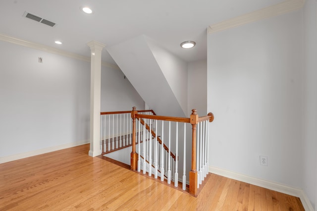 interior space featuring baseboards, visible vents, wood finished floors, crown molding, and an upstairs landing