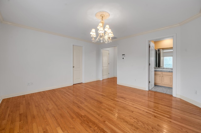 spare room featuring light wood finished floors, crown molding, baseboards, and a notable chandelier