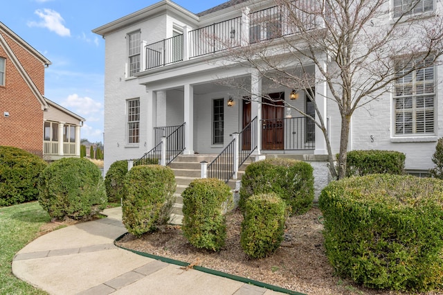 view of front of home with covered porch, brick siding, and a balcony