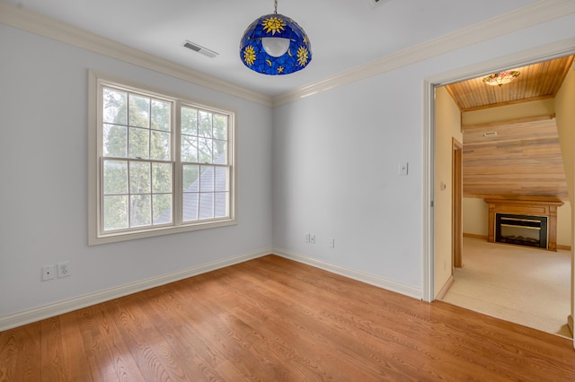 spare room with ornamental molding, wood finished floors, visible vents, and baseboards