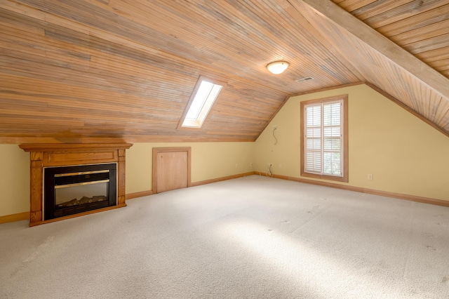 bonus room featuring vaulted ceiling with skylight, baseboards, a glass covered fireplace, light colored carpet, and wood ceiling