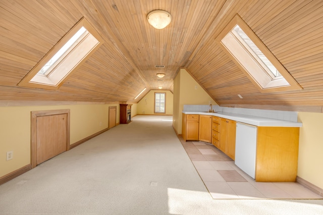 additional living space featuring vaulted ceiling with skylight, wooden ceiling, light carpet, a sink, and baseboards