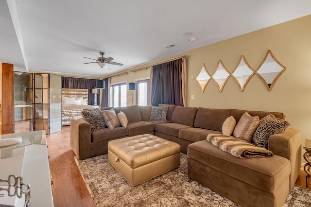 living room with visible vents, ceiling fan, and hardwood / wood-style flooring