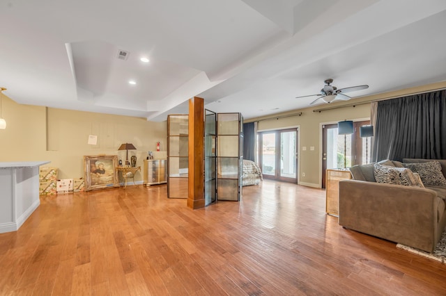 living room featuring baseboards, a ceiling fan, light wood-style flooring, a tray ceiling, and recessed lighting