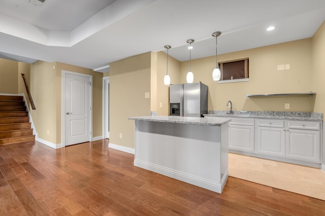 kitchen with baseboards, light wood-style flooring, light stone countertops, white cabinetry, and stainless steel refrigerator with ice dispenser