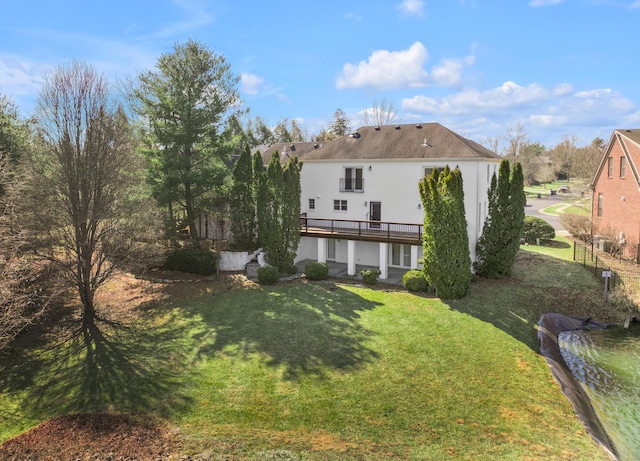 rear view of house with a yard, a deck, and stucco siding