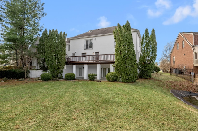 back of house featuring stucco siding, a lawn, and fence