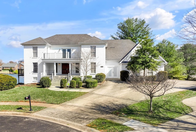 view of front of home with a porch, a front yard, driveway, and a balcony