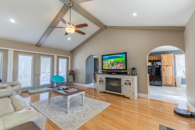 living area featuring arched walkways, vaulted ceiling with beams, recessed lighting, baseboards, and light wood-type flooring