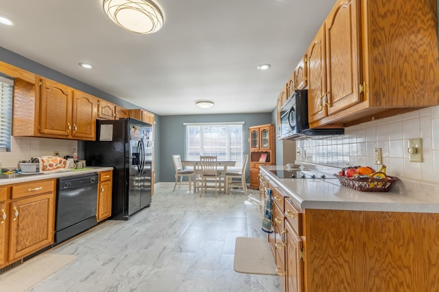 kitchen featuring brown cabinets, light countertops, decorative backsplash, black appliances, and baseboards