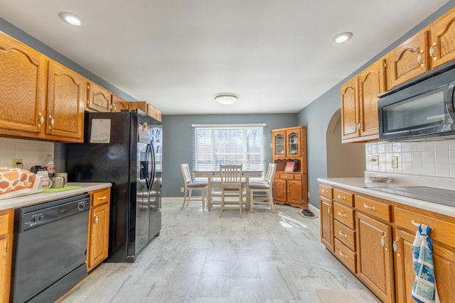 kitchen featuring black appliances, tasteful backsplash, light countertops, and baseboards