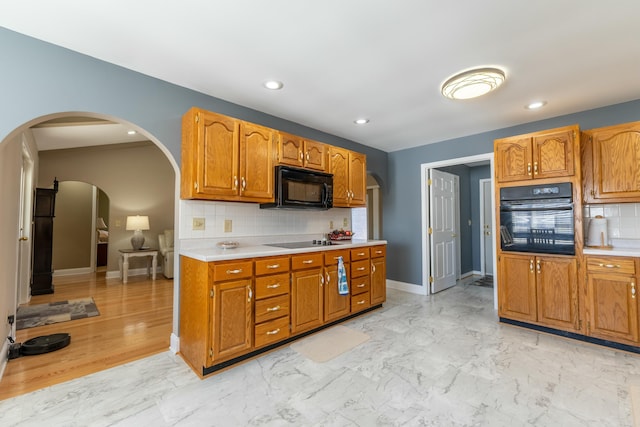 kitchen with baseboards, arched walkways, marble finish floor, light countertops, and black appliances