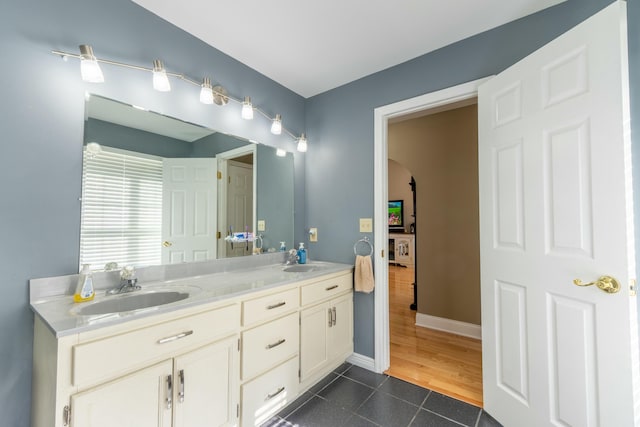 full bath featuring double vanity, tile patterned flooring, baseboards, and a sink