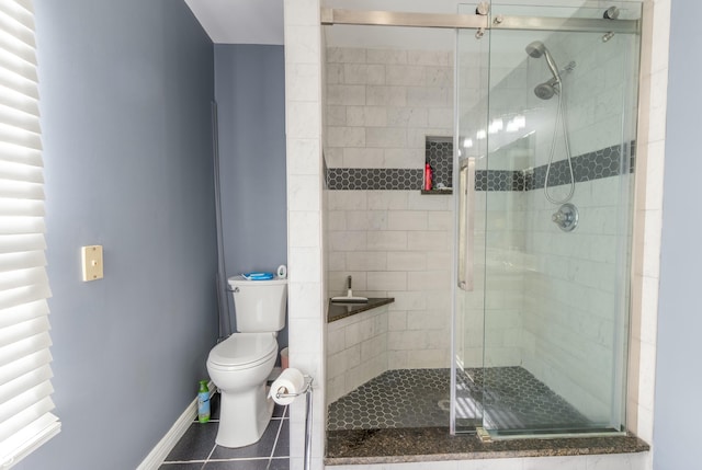 bathroom with tile patterned flooring, a shower stall, toilet, and baseboards