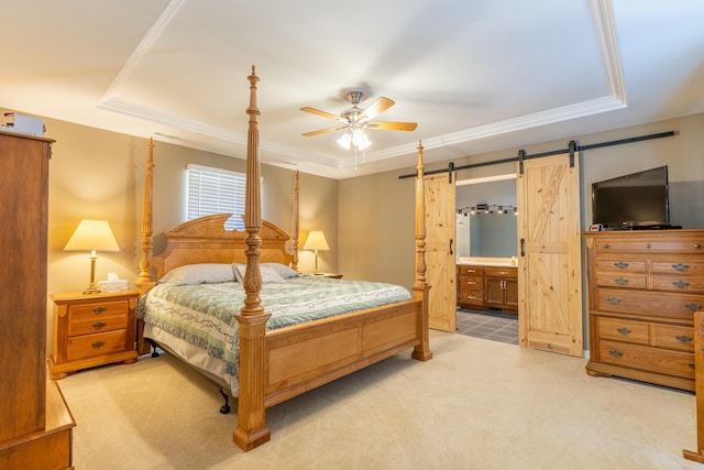 bedroom with light carpet, a barn door, a tray ceiling, and crown molding