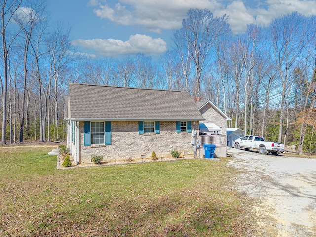 view of front of house featuring driveway, brick siding, roof with shingles, and a front yard