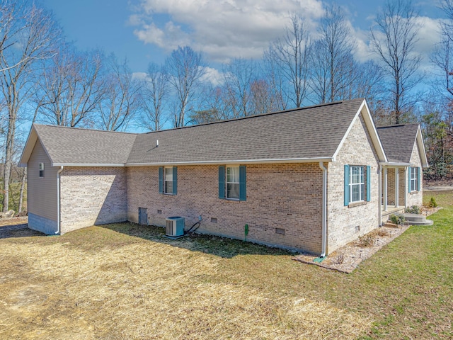 back of house with brick siding, crawl space, a shingled roof, and a lawn