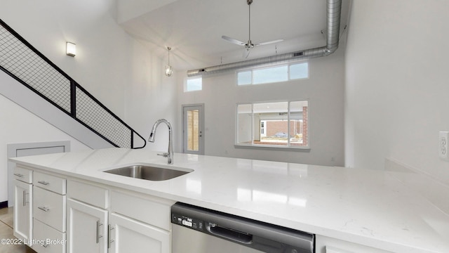 kitchen featuring a ceiling fan, a sink, light stone countertops, white cabinetry, and stainless steel dishwasher