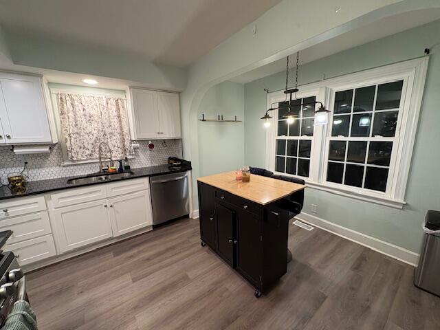 kitchen with tasteful backsplash, appliances with stainless steel finishes, a sink, and white cabinets