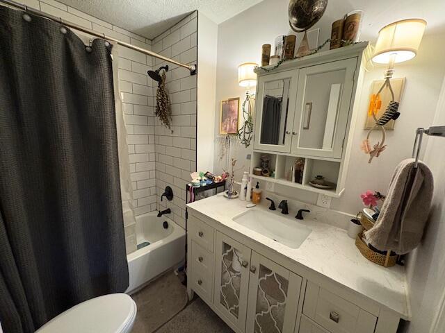 full bath with shower / tub combo with curtain, a textured ceiling, toilet, and vanity