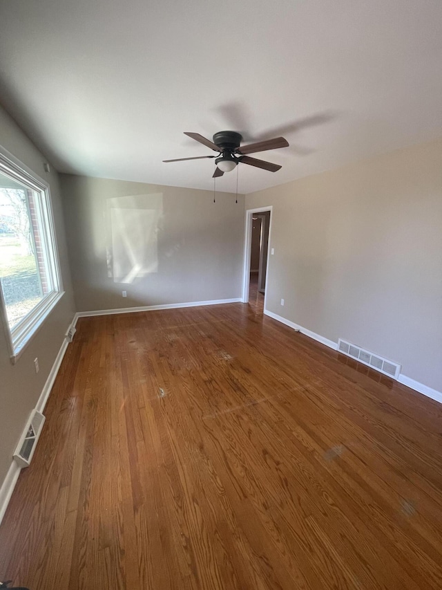 unfurnished room featuring ceiling fan, wood finished floors, visible vents, and baseboards