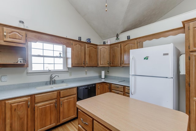 kitchen featuring a sink, vaulted ceiling, light countertops, freestanding refrigerator, and dishwasher