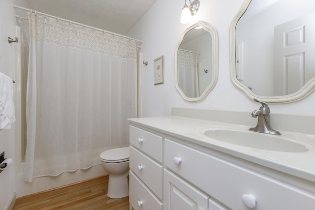 bathroom featuring shower / tub combo, toilet, wood finished floors, a textured ceiling, and vanity