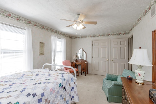 bedroom featuring a textured ceiling, ceiling fan, a closet, and light colored carpet