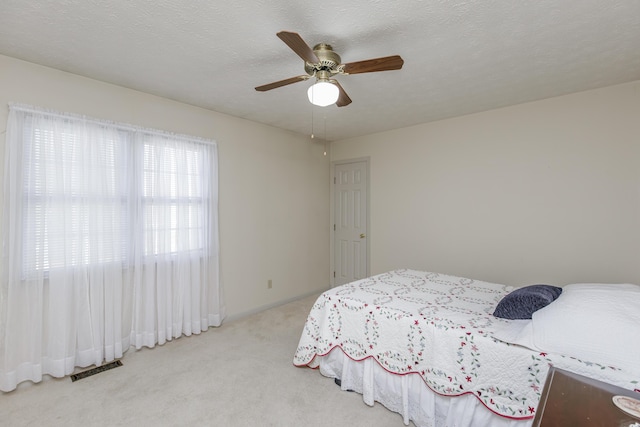 bedroom featuring a textured ceiling, ceiling fan, carpet, and visible vents