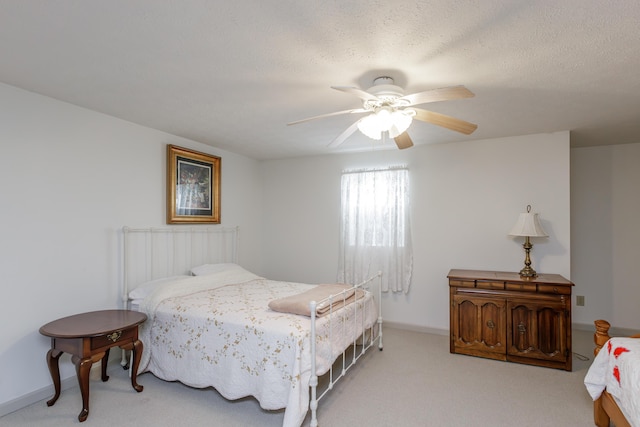 carpeted bedroom with a textured ceiling, a ceiling fan, and baseboards