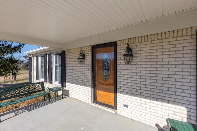 property entrance with covered porch and brick siding