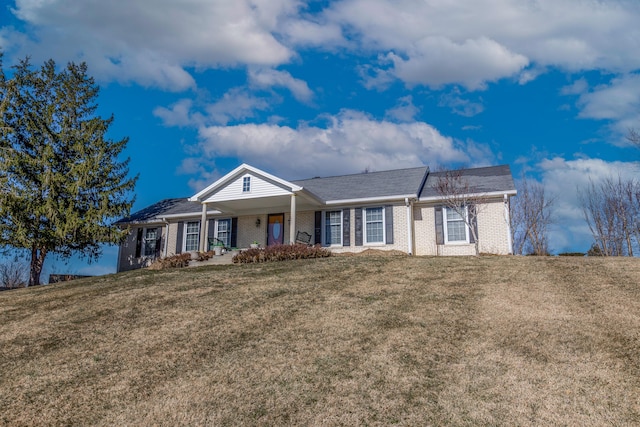 ranch-style home featuring a porch, brick siding, and a front lawn