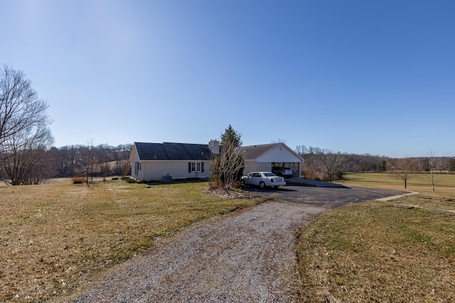 view of front of home featuring driveway, a chimney, and a front yard