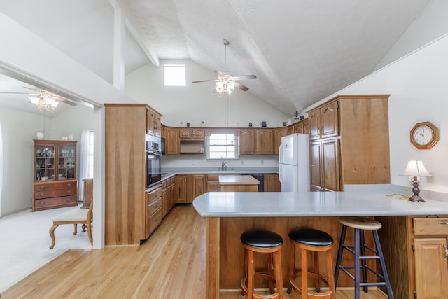 kitchen with ceiling fan, a peninsula, light countertops, and freestanding refrigerator