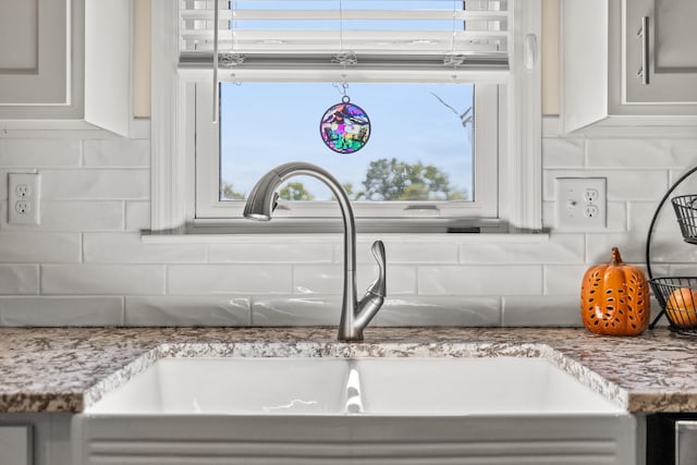 interior details featuring tasteful backsplash, white cabinetry, and a sink