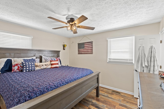 bedroom with a textured ceiling, ceiling fan, wood finished floors, visible vents, and baseboards